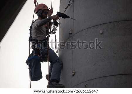 Man using a rotary hammer drill while working on a concrete chimney