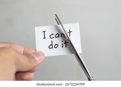 Man using scissors to remove the word can't to read I can do it. Concept for self belief, positive attitude, and motivation.