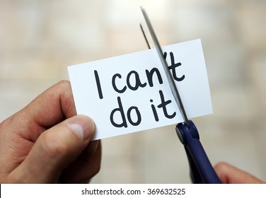Man using scissors to remove the word can't to read I can do it concept for self belief, positive attitude and  motivation