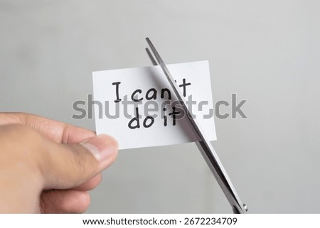 Man using scissors to remove the word can't to read I can do it. Concept for self belief, positive attitude, and motivation.