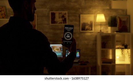 Man using a smart lights app to turn on the lights in the living room. Smart technology and application