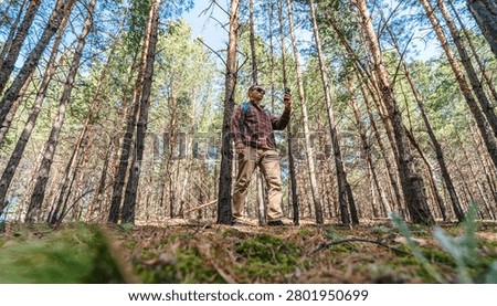 man using smart phone in the backwoods in summertime 