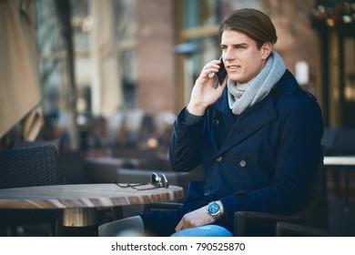Man using smart phone and drinking coffee while sitting in cafe.