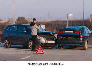 A Man Using A Smart Phone To Take A Photo Of The Damage To His Car Caused By A Car Crash