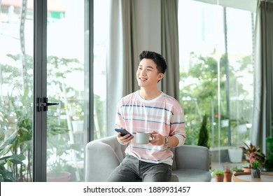 Man Using A Smart Phone While Drinking Coffee At Home