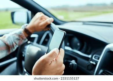 Man using a smart phone while driving a car on the road - Powered by Shutterstock