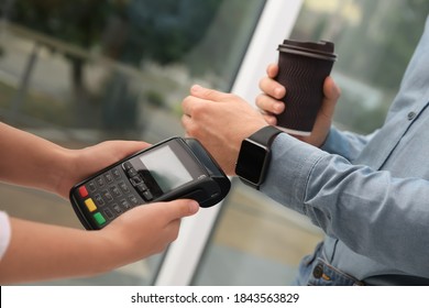 Man using smart watch for contactless payment via terminal in cafe, closeup - Powered by Shutterstock