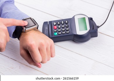 Man using smart watch to express pay on a wooden table - Powered by Shutterstock