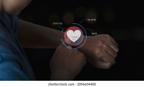 Man Using Smart Watch Technology Checking Heart Rate With Health App Icon On The Screen. Holographic Icon User Interface. Futuristic Smart Watch Technology. Healthcare Concept.