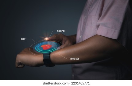 Man using smart watch technology checking heart rate with health app icon on the screen. Holographic icon user interface. Futuristic smart watch technology. Healthcare concept. - Powered by Shutterstock