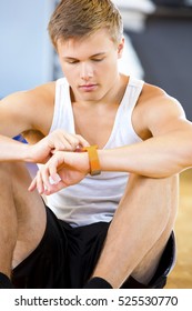 Man Using Smart Watch While Sitting In Gym