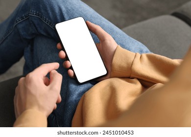 Man using smartphone with blank screen indoors, closeup. Mockup for design