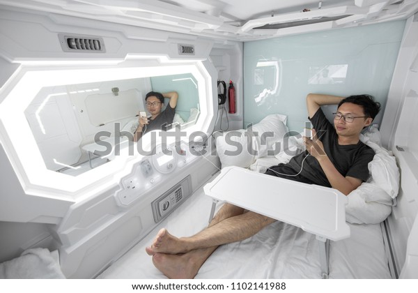 man using\
smartphone in the capsule\
hotel.