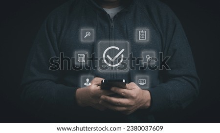 Man using smartphone to checking quality assurance and approval for service guarantee, certification, standardization, quality control and service approval concept.