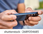 Man using smartphone, close up. Male hands holding smartphone and playing mobile game outdoors. Concept of technology, digital entertainment and gadget using