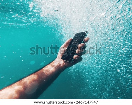 Man using smartphone device underwater in deep blue sea during summer holiday vacation, selective focus