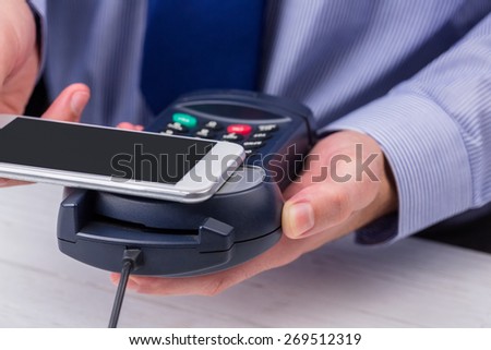 Man using smartphone to express pay on a wooden table