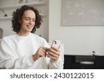 Man using smartphone at home, looking at mobile phone