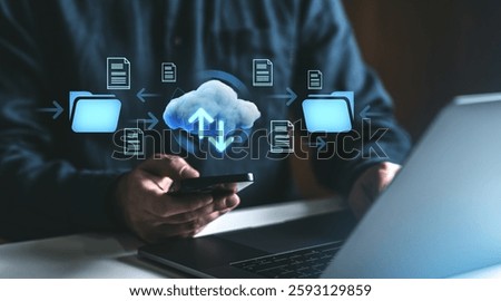 Man using smartphone and laptop with cloud storage icons, folders, and arrows representing online data transfer. Digital network technology concept