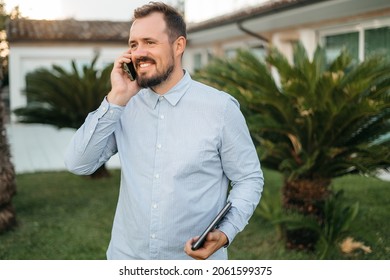 Man Using Smartphone Outdoor. Portrait Of Young Businessman Using Mobile Phone While Looking Away On The Street. Thoughtful Business Man In Blue Formal Clothing Using Cellphone Outside . 