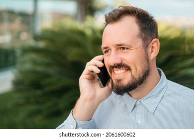 Man Using Smartphone Outdoor. Portrait Of Young Businessman Using Mobile Phone While Looking Away On The Street. Thoughtful Business Man In Blue Formal Clothing Using Cellphone Outside 