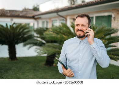 Man Using Smartphone Outdoor. Portrait Of Young Businessman Using Mobile Phone While Looking Away On The Street. Thoughtful Business Man In Blue Formal Clothing Using Cellphone Outside 