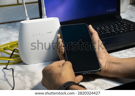 The man is using a smartphone and router, high-speed internet connection, network bandwidth technology, and speed optimization.