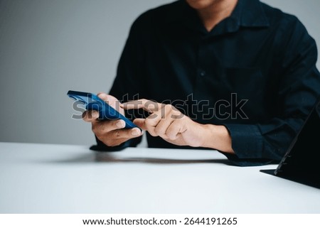 Man using smartphone and stylus at clean tech desk. Modern business communication, digital interface, touchscreen tech, and mobile productivity concept.