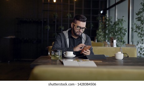 Man using smartphone at table in cafe