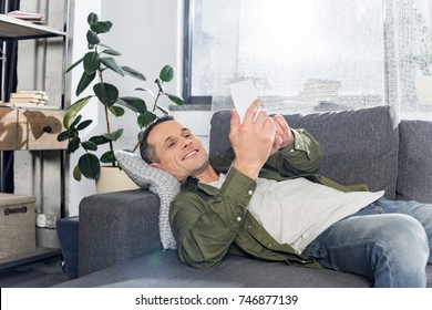 man using smartphone while laying on couch