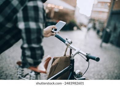 Man using smartphone while riding bicycle in city