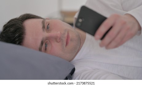 Man Using Smartphone While Sleeping In Bed, Close Up