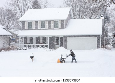 Man using a snowblower to clear his sidewalk and driveway - Powered by Shutterstock