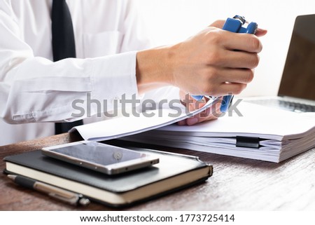 Man using stapler with documents on the table