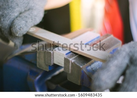 A man using the steel rasp to decorate the work , the hammer to sharpen