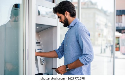 Man using a street ATM machine and withdrawing money 