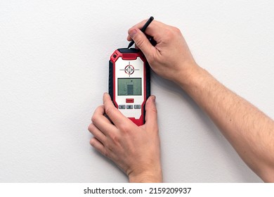 Man using stud finder to locate framing studs located behind the walling surface. Using a wall scanner to identify hidden electrical wiring. Space for text.