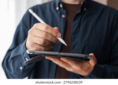 Man using a stylus on a tablet in a folio case for digital note taking, drawing and app interface design background for productivity and education.