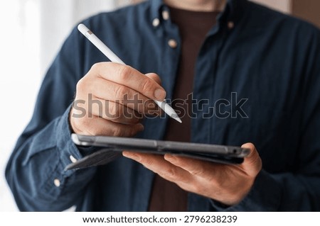 Man using a stylus on a tablet in a folio case for digital note taking, drawing and app interface design background for productivity and education.