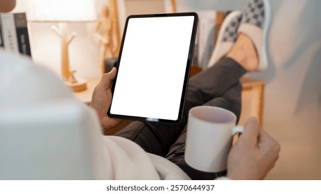 Man Using tablet with blank screen for design mockup device, sitting in living room at home, work from home
