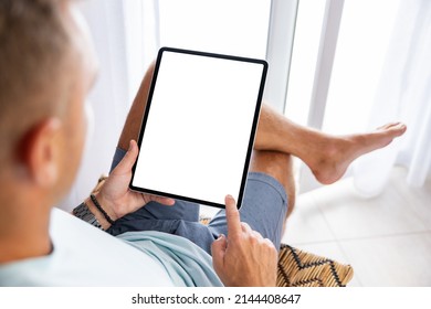 Man using tablet computer at home, empty blank vertical screen mockup