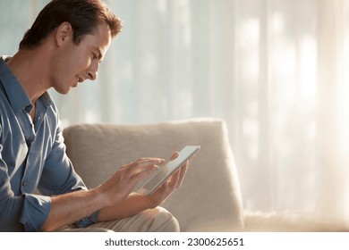 Man using tablet computer on sofa