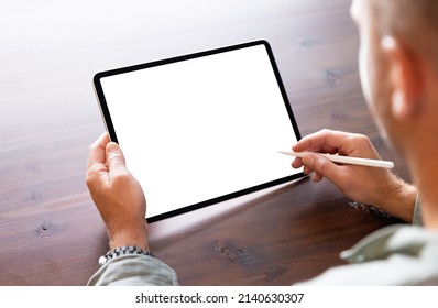 Man Using Tablet Computer With Stylus Pen, Empty White Screen Mockup, Over The Shoulder View