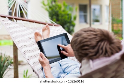 Man using a tablet computer while relaxing in a hammock - Powered by Shutterstock