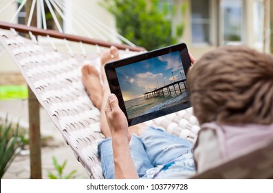 Man using a tablet computer while relaxing in a hammock - Powered by Shutterstock