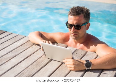 Man using tablet computer while relaxing in the pool - Powered by Shutterstock