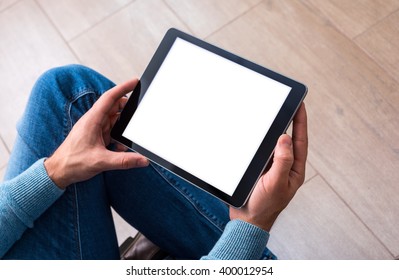 Man using tablet computer while sitting on a wooden floor. View from above. Clipping path included.
