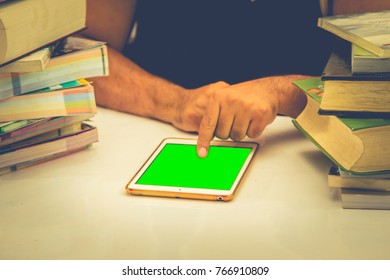 man is using tablet during reading a book