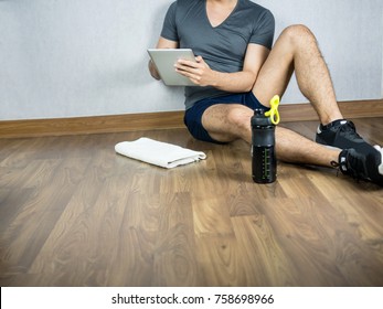 Man using tablet for exercise, sit with sport water bottle and towel