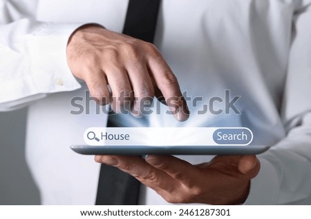 Man using tablet to find house, closeup. Search bar over device